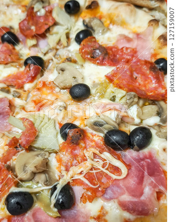 Close up of freshly baked pizza showcasing variety of toppings including olives, mushrooms, and meats, italian cuisine 127159007