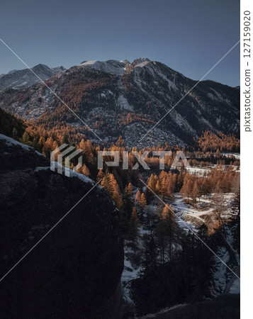 Warm autumn sunlight casts a golden glow on the snow dusted mountains and forests of aosta, italy, creating a picturesque november landscape Lillaz Warm autumn sunlight casts a golden glow on the snow dusted mountains and forests of aosta, italy, creating a picturesque november landscape Lillaz 127159020