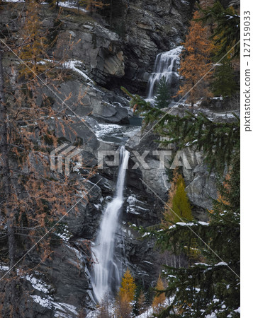 Majestic waterfalls cascade down rocky cliffs surrounded by autumn foliage in aosta, italy, capturing the serene beauty of november Lillaz 127159033