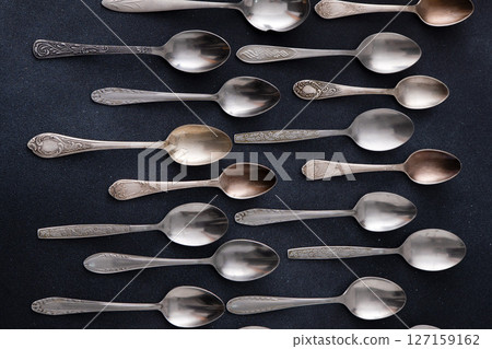 Set of different spoons. Silver cutlery on a black background. Spoon on the table 127159162