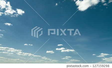 An Expansive Display of a Blue Sky, Showcasing Fluffy White Clouds Against a Bright Horizon 127159298