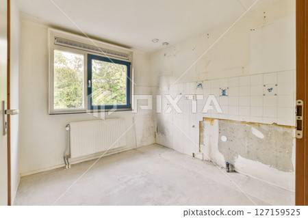 A vacant room showcasing bare walls and a window offering natural light. The space is ready for renovation or decoration. 127159525