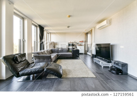 A sleek, modern living room featuring large windows that invite natural light, minimalist furniture, and a cozy atmosphere. Perfect for contemporary living styles. 127159561