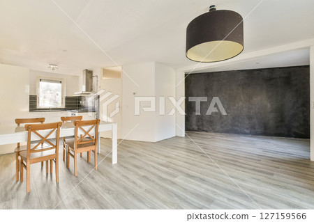 A bright and open modern kitchen features a sleek design with minimalist decor. The dining area has a simple table and chairs, enhancing the uncluttered aesthetic. 127159566