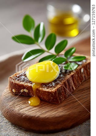 Glistening molten egg-butter with runny yolk covers traditional Finnish karjalanpiirakka on textured wooden board. Rustic kitchen setting. Concept of culinary arts, traditional baking, Nordic cuisine 127159763