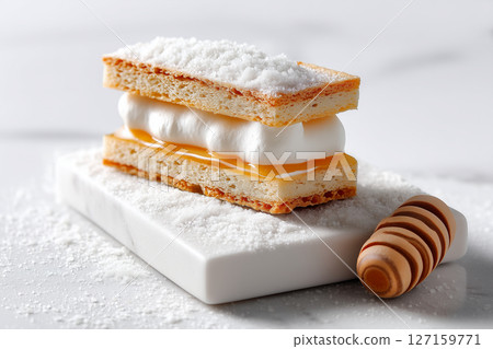 Minimalist photo of dessert pastry with sugar on white marble board. Pastry layers feature creamy filling and sugar topping. Concept of bakery, dessert, culinary arts Minimalist photo of dessert pastry with sugar on white marble board. Pastry layers feature creamy filling and sugar topping. Concept of bakery, dessert, culinary arts 127159771