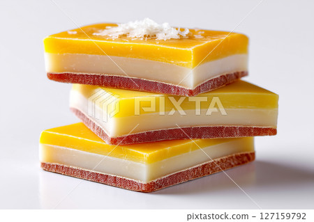 Gouda cheese slices layered with wax edge displayed against a clean white backdrop. Concept of culinary arts, cheese production, gourmet food photography 127159792