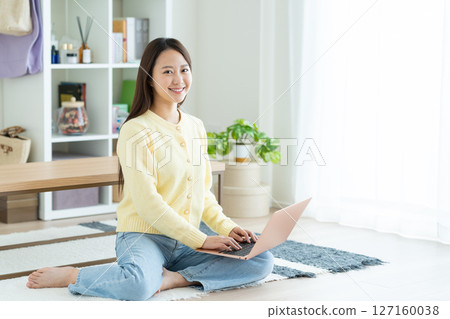 A young lady who plays a personal computer in the living room A young lady who plays a personal computer in the living room 127160038