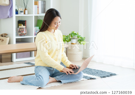 A young lady who plays a personal computer in the living room 127160039
