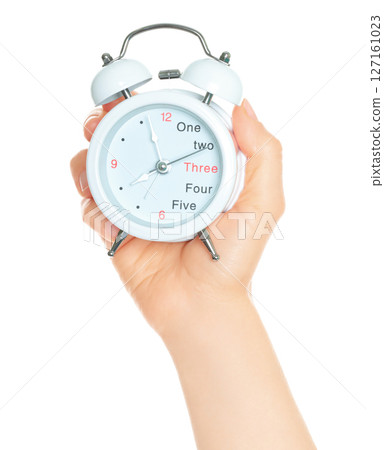 Woman hand holds white Alarm Clock, isolated on transparent background, time and home things concept 127161023