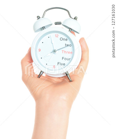 Woman hand holds white Alarm Clock, isolated on transparent background, time and home things concept 127161030