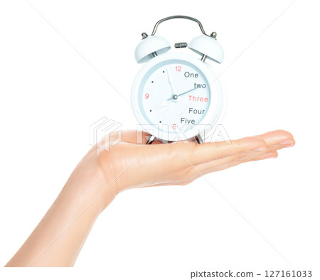 Woman hand holds white Alarm Clock, isolated on transparent background, time and home things concept Woman hand holds white Alarm Clock, isolated on transparent background, time and home things concept 127161033