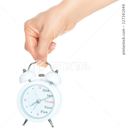 Woman hand holds white Alarm Clock, isolated on transparent background, time and home things concept 127161049