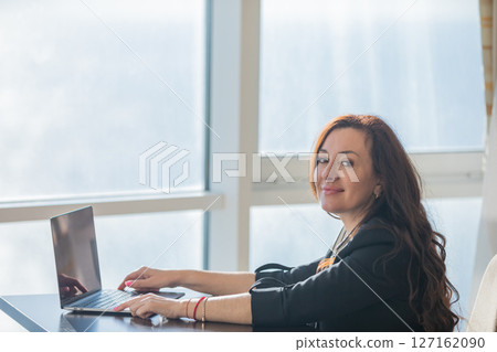 woman working on laptop online and smiling in office woman working on laptop online and smiling in office 127162090
