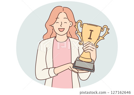 Happy woman with trophy cup in hands smiles and looks at screen showing off achievements 127162646