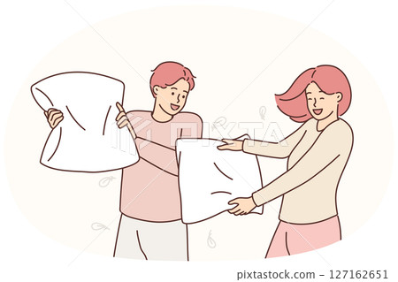 Smiling couple involved in pillow fight Smiling couple involved in pillow fight 127162651