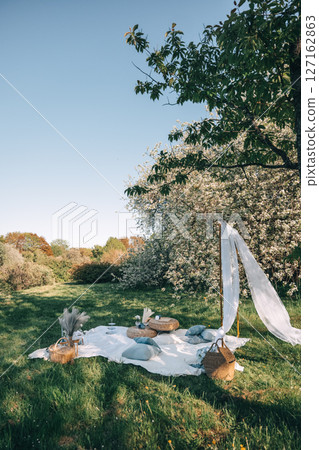 Relaxing outdoor picnic setup in a serene garden on a sunny day Relaxing outdoor picnic setup in a serene garden on a sunny day 127162863