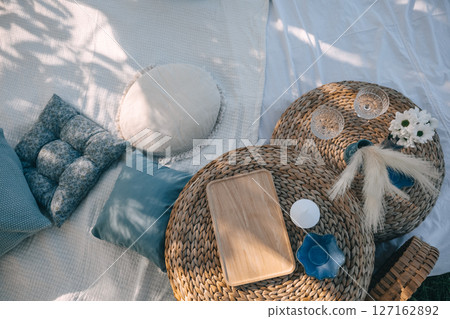 Cozy outdoor setting with woven tables, cushions, and decorative elements during daytime 127162892