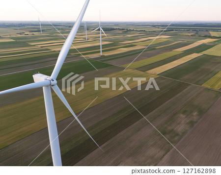 Aerial view of wind turbine on an agricultural filed at sunset. Close up of blades 127162898