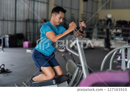 Fitness Focus. Man using elliptical machine for cardio workout. 127163910