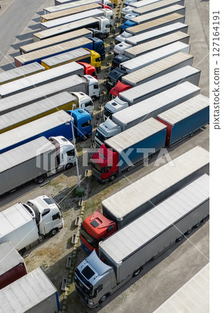 Aerial view of a large truck parking lot at a logistics hub, with multiple commercial semi trucks parked in organized rows 127164191