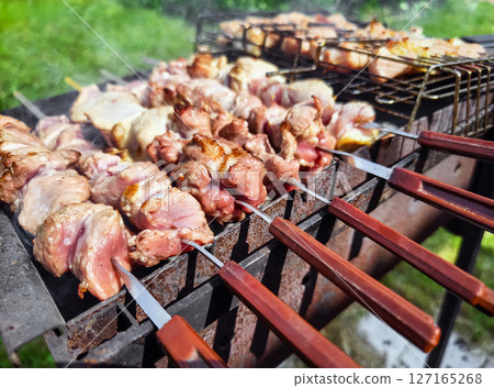 Grilling skewers at a summer barbecue gathering in a backyard setting with friends and family enjoying outdoor cooking 127165268