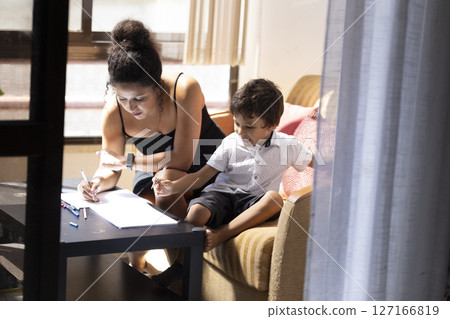 Mother helping son with homework, homeschooling during quarantine 127166819