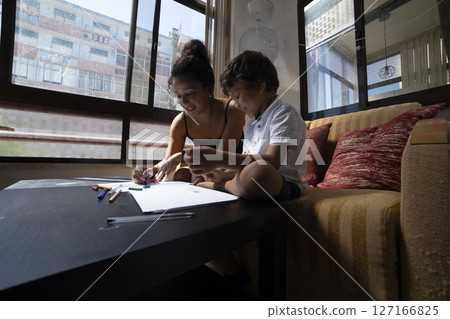 Mother and son drawing together at home, enjoying quality time Mother and son drawing together at home, enjoying quality time 127166825