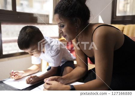 Mother helping son with homework, supporting education at home Mother helping son with homework, supporting education at home 127166880