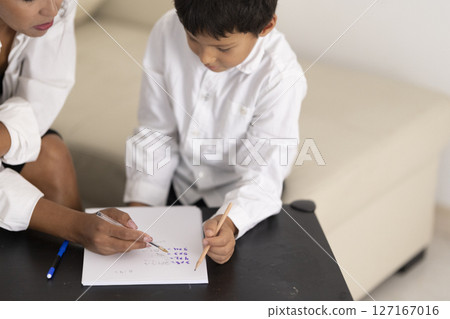 Teacher helping young boy learning handwriting skills Teacher helping young boy learning handwriting skills 127167016