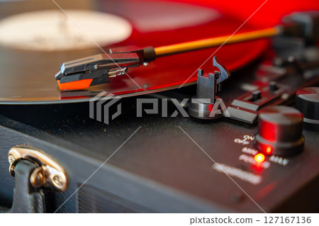 Close-up of record player needle tracking vinyl grooves during playback. Analog sound detail capturing retro music atmosphere. 127167136