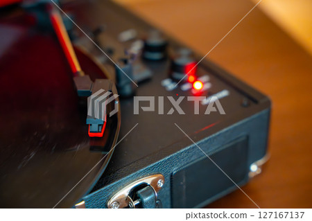 Close-up of record player needle tracking vinyl grooves during playback. Analog sound detail capturing retro music atmosphere. 127167137