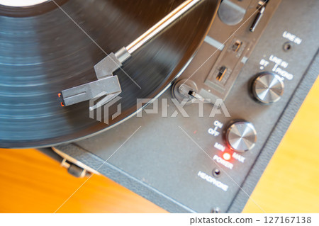 Close-up of record player needle tracking vinyl grooves during playback. Analog sound detail capturing retro music atmosphere. 127167138