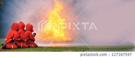 Firefighter Rescue training in fire fighting extinguisher. Firefighter fighting with flame using fire hose chemical water foam spray engine. Fireman wear hard hat, safety suit uniform for protection 127167597