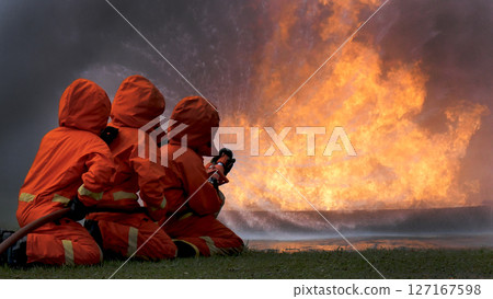 Firefighter Rescue team training in fire fighting extinguisher. Teamwork Firefighter fighting with flame using fire hose chemical water foam spray engine. Fireman teams wear hard hat safety uniform Firefighter Rescue team training in fire fighting extinguisher. Teamwork Firefighter fighting with flame using fire hose chemical water foam spray engine. Fireman teams wear hard hat safety uniform 127167598