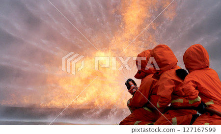 Firefighter Rescue team training in fire fighting extinguisher. Teamwork Firefighter fighting with flame using fire hose chemical water foam spray engine. Fireman teams wear hard hat safety uniform 127167599