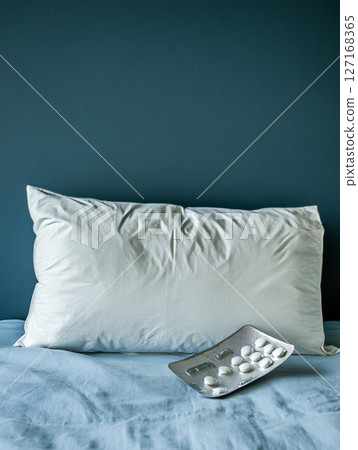 White Pillow and Medication Blister Pack on a Bed 127168365