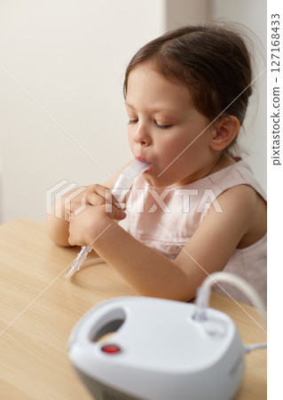 cute little toddler girl inhaling medicine on nebulizer and holding it on her own, portable inhaler for home cute little toddler girl inhaling medicine on nebulizer and holding it on her own, portable inhaler for home 127168433