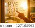 A hand writes BYE SCHOOL on a foggy window, embodying the joyful end of academic year and anticipation of summer break 127168593