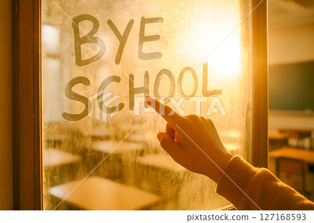A hand writes BYE SCHOOL on a foggy window, embodying the joyful end of academic year and anticipation of summer break 127168593