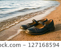 Classic Mary Jane shoes rest on a golden sandy beach by gentle waves, symbolizing serene escape, peaceful relaxation, and a well-deserved break from routine 127168594