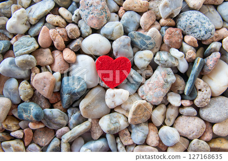 Red bright fabric heart on other stones near the river. 127168635