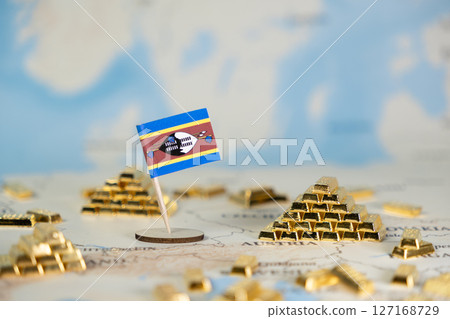 Eswatini flag prominently displayed among numerous shimmering gold bars on a world map, representing national wealth, economic growth, and global trade 127168729