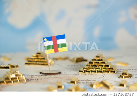 Central African Republic flag standing beside gleaming gold bar piles on a world map, representing national economic resources, investment, and wealth management, with copy space Central African Republic flag standing beside gleaming gold bar piles on a world map, representing national economic resources, investment, and wealth management, with copy space 127168737