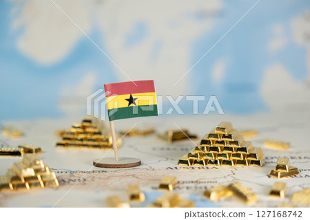 Ghanaian flag standing amidst glittering gold bars on a world map, reflecting the nation's rich natural resources and economic potential with ample copy space 127168742
