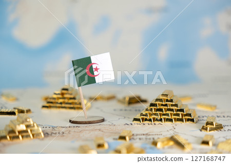 Algerian flag positioned among miniature gold bars on a blurred global map, representing national wealth, economic power, and strategic resource management, with ample blank copy space Algerian flag positioned among miniature gold bars on a blurred global map, representing national wealth, economic power, and strategic resource management, with ample blank copy space 127168747