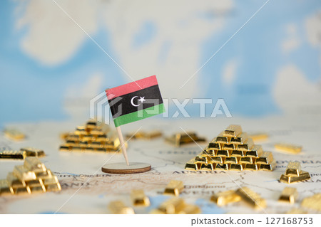 Libyan flag stands prominently amidst glittering gold bars on a world map, symbolizing national wealth, economic power, and global financial market stability 127168753
