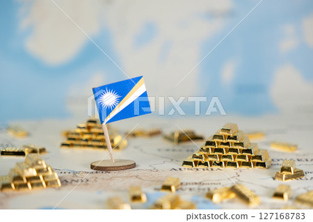Marshall Islands flag stands among gleaming gold bars on a world map, symbolizing national wealth, economic strength, and global investment with copy space 127168783
