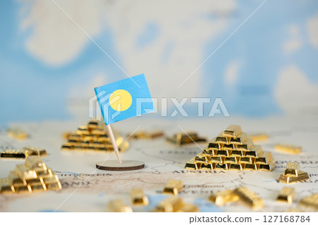 Palau flag proudly standing amidst shining gold bars on a world map, symbolizing national economic prosperity, international finance, and strategic global investment, with clear copy space 127168784