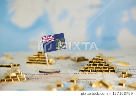 British Virgin Islands flag pin stands among scattered gold bar stacks on a world map, symbolizing offshore finance and global wealth management concepts with ample copy space 127168799